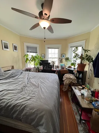 a bedroom with a bed couch chandelier and a window