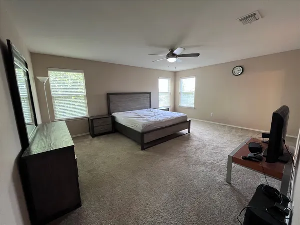 a spacious bedroom with a bed and a ceiling fan