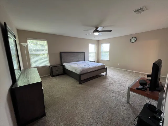 a spacious bedroom with a bed and a ceiling fan