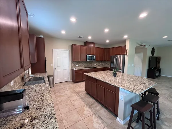 a kitchen with stainless steel appliances granite countertop a sink a stove and a refrigerator