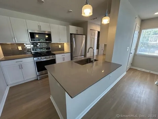 a kitchen with kitchen island a counter space a sink appliances and cabinets