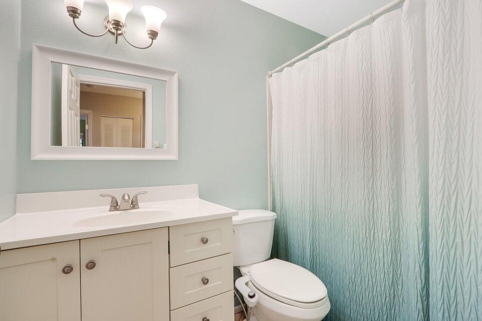 1258 Southeast Rickenbacker Terrace Port St. Lucie, FL 34952 - Photo 19 of 29 a bathroom with a sink a toilet and shower curtain