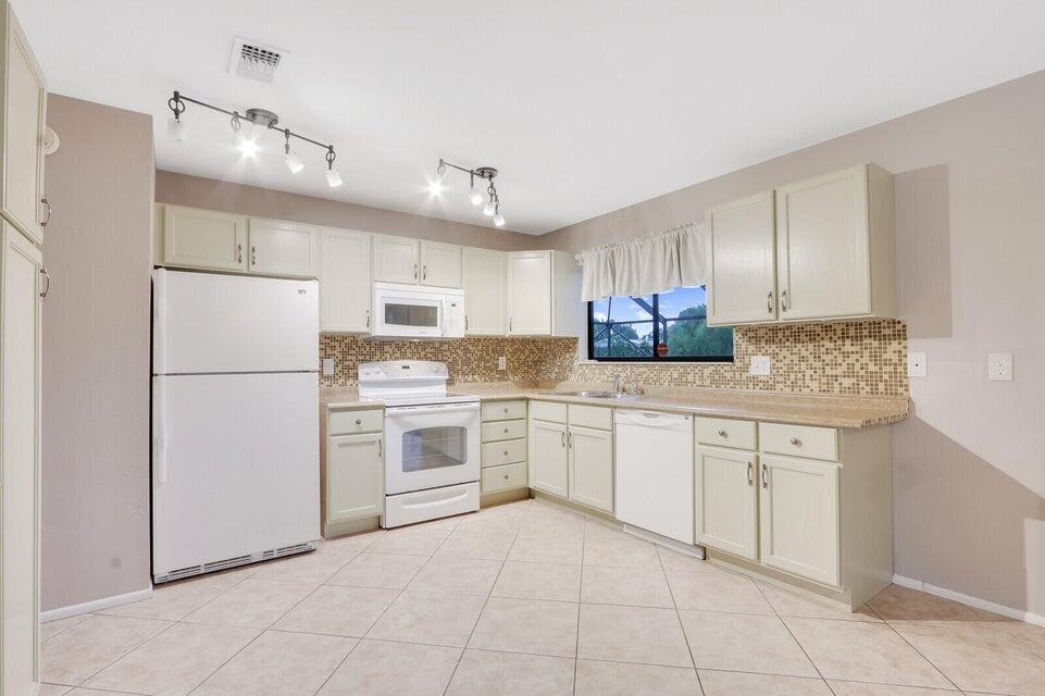 1258 Southeast Rickenbacker Terrace Port St. Lucie, FL 34952 - Photo 9 of 29 a kitchen with granite countertop cabinets and white stainless steel appliances