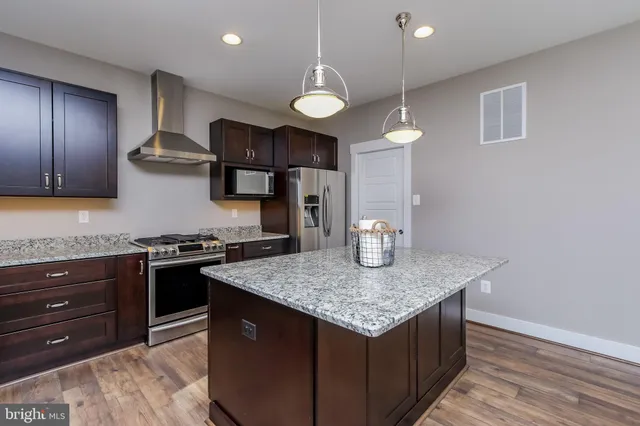 a kitchen with stainless steel appliances granite countertop a stove a sink and a refrigerator