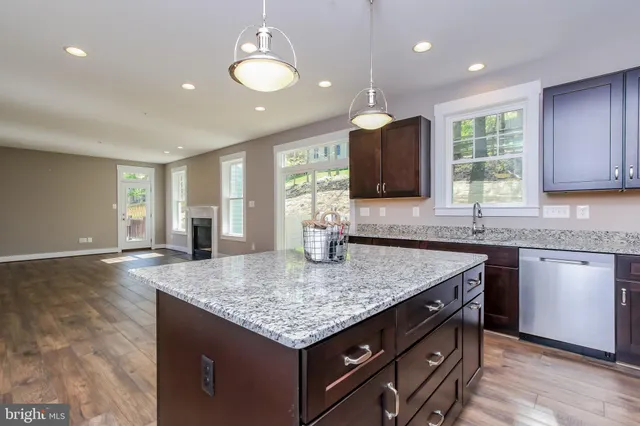 a kitchen with granite countertop kitchen island a sink dishwasher a dining table and chairs with wooden floor