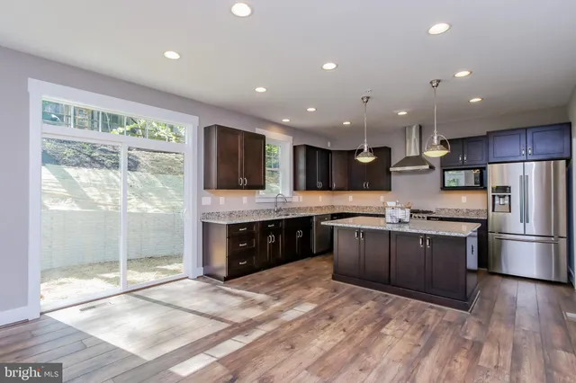 a large kitchen with stainless steel appliances kitchen island granite countertop a stove a refrigerator a sink dishwasher a oven and a dining table with wooden floor