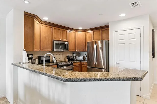 a kitchen with granite countertop a sink a counter top space cabinets and stainless steel appliances