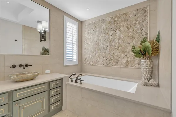 a bathroom with a granite countertop sink a large mirror and a bathtub