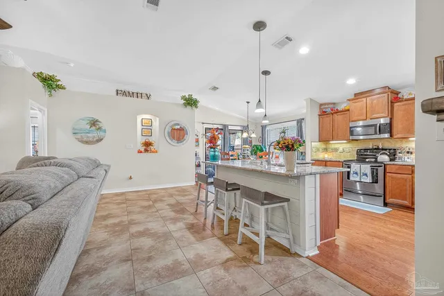 a kitchen with stainless steel appliances granite countertop a refrigerator a sink dishwasher and a stove with wooden floor