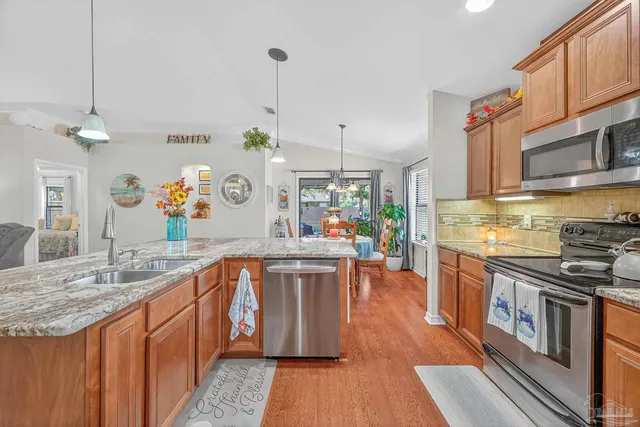 a kitchen with stainless steel appliances granite countertop a refrigerator a stove and a sink