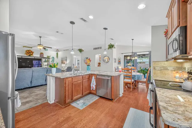 a kitchen with stainless steel appliances kitchen island granite countertop a refrigerator stove top oven and sink