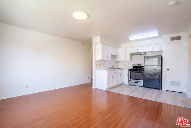 a kitchen with granite countertop a refrigerator and wooden floor