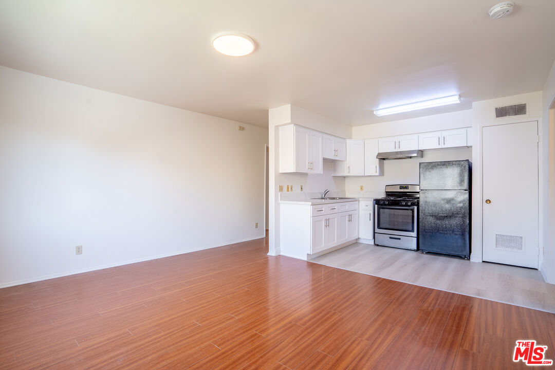 820 South St Andrews Place, Unit 304 Los Angeles, CA 90005 - Photo 3 of 16 a kitchen with granite countertop a refrigerator and wooden floor