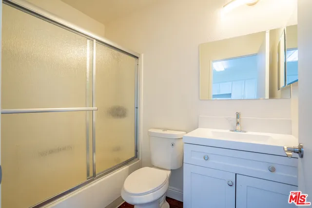 a bathroom with a sink a mirror a toilet and shower