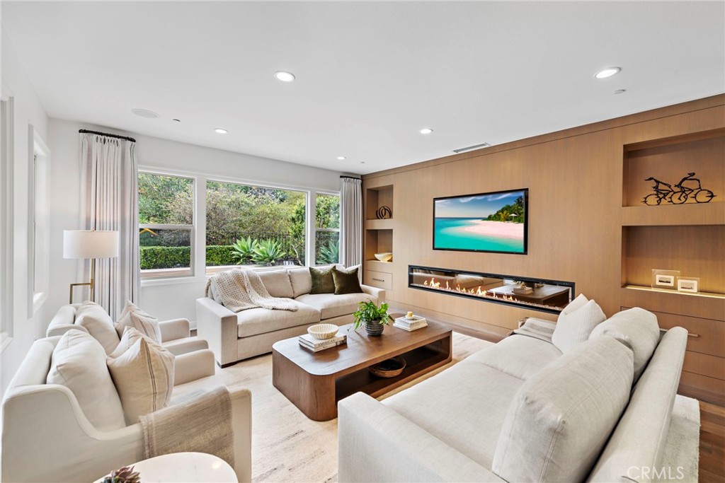 a living room with furniture floor to ceiling window hardwood floor and a flat screen tv