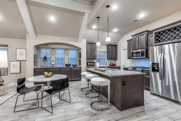 a kitchen with stainless steel appliances granite countertop a stove refrigerator and chairs