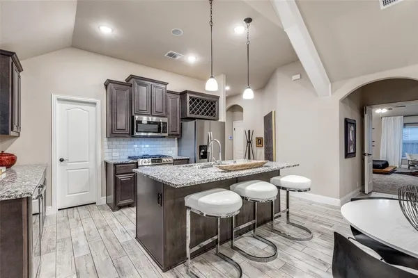 a kitchen with stainless steel appliances granite countertop a sink a stove and a wooden floors