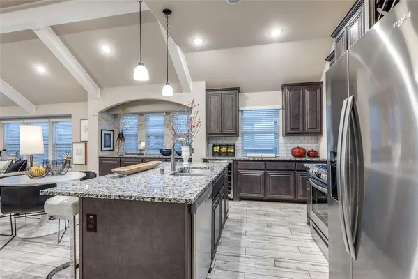 a large kitchen with granite countertop lots of counter top space and stainless steel appliances