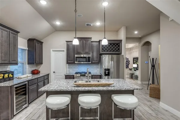 a kitchen with kitchen island granite countertop a sink and refrigerator