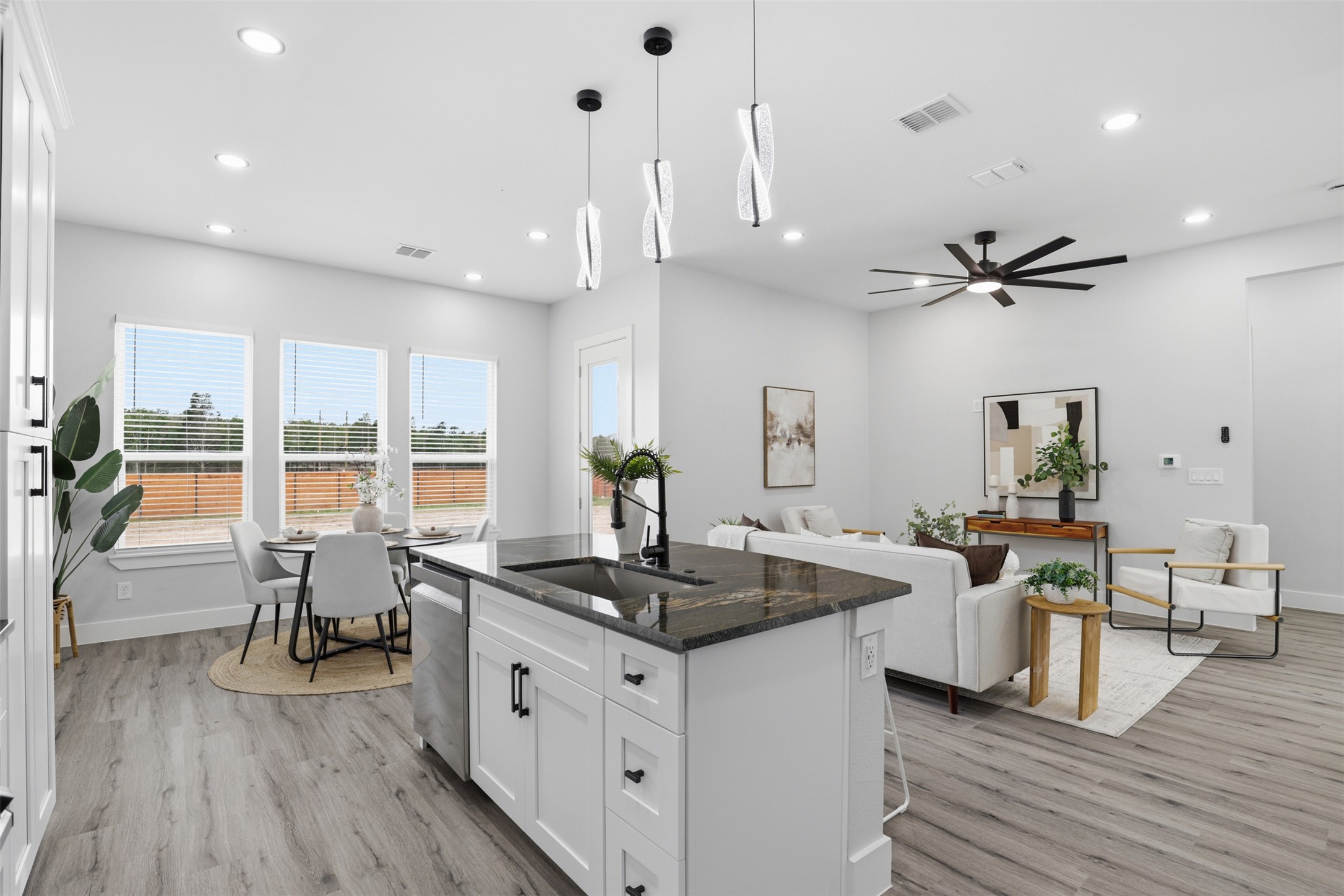 113 Los Robles Road Elgin, TX 78621 - Photo 3 of 20 Open-concept living space featuring wood-finish flooring, a kitchen island with stone countertops, recessed lighting, a ceiling fan, and multiple windows
