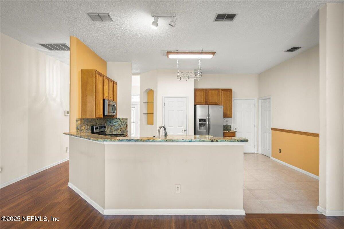 1385 Soaring Flight Way Jacksonville, FL 32225 - Photo 8 of 34 a large white kitchen with kitchen island a sink a stove and wooden floor