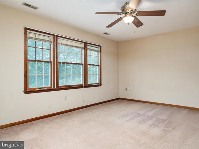 an empty room with chandelier fan and windows