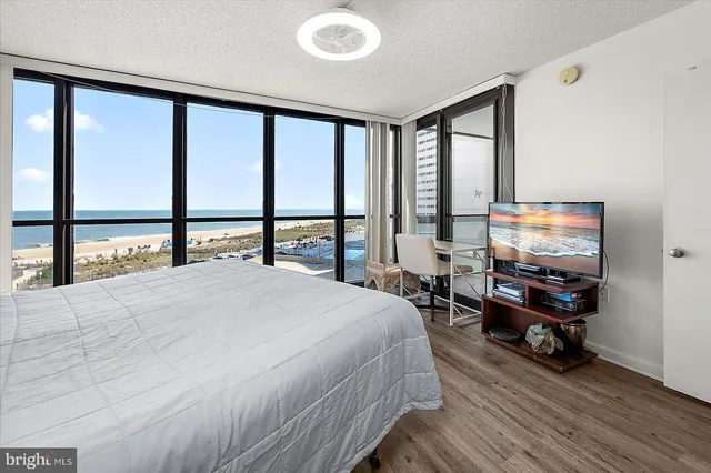 a bedroom with a bed table and two flat screen tv
