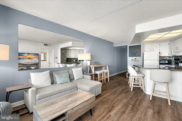 a kitchen with stainless steel appliances granite countertop a stove a refrigerator a microwave a dining table and chairs with wooden floor