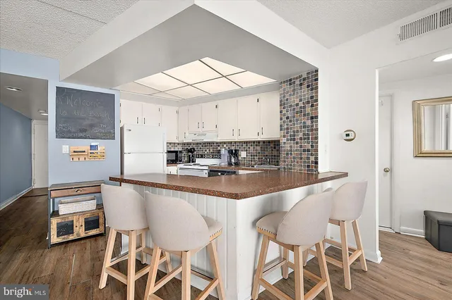 a kitchen with stainless steel appliances granite countertop a sink a refrigerator a stove a dining table and chairs