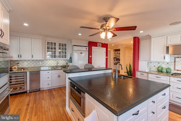 a kitchen with stainless steel appliances granite countertop a sink a stove and chairs