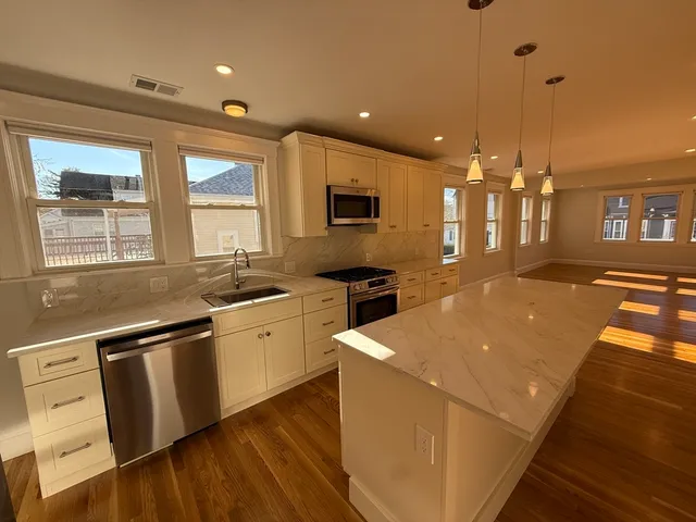 a large kitchen with stainless steel appliances kitchen island granite countertop a sink and cabinets