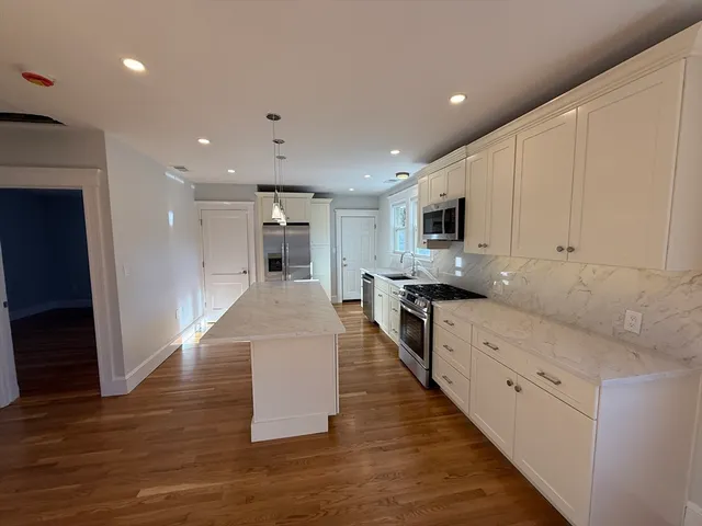 a large kitchen with stainless steel appliances granite countertop a large counter top and a stove top oven