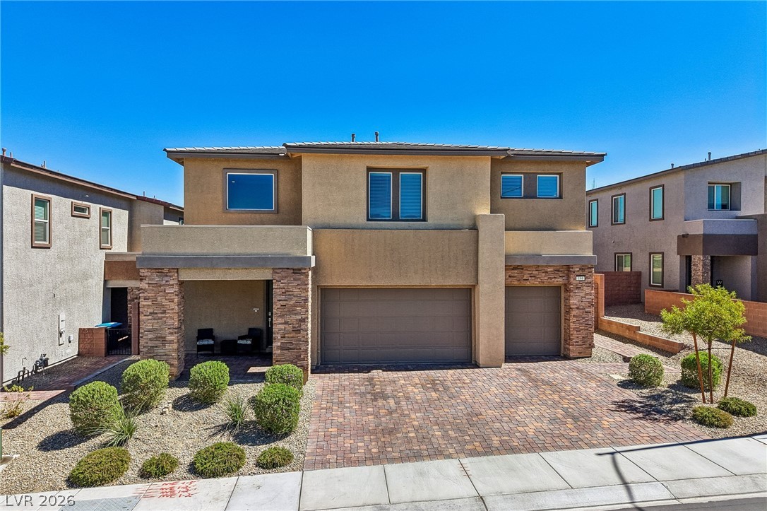 194 Viento Ridge Street Henderson, NV 89012 - Photo 57 of 72 An inviting stone-accented facade showcases a spacious paver driveway under clear blue skies.