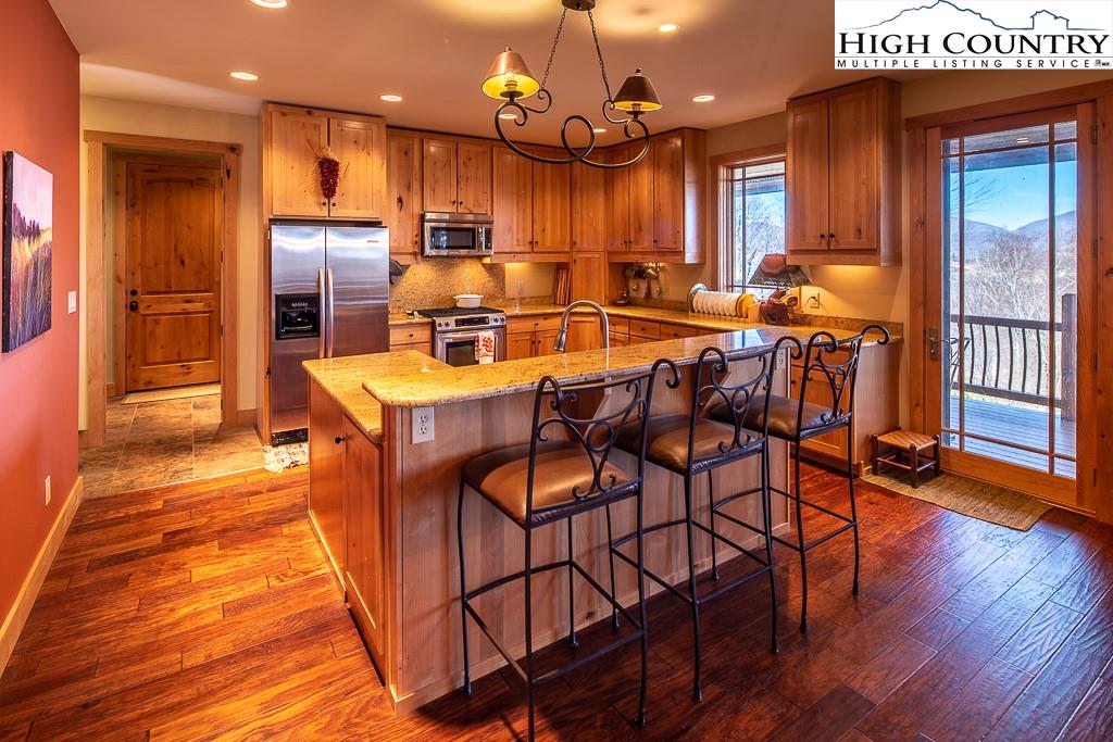 612 Bear Cubs Trail Boone, NC 28607 - Photo 12 of 37 a dining room with stainless steel appliances kitchen island granite countertop wooden floor a dining table and chairs