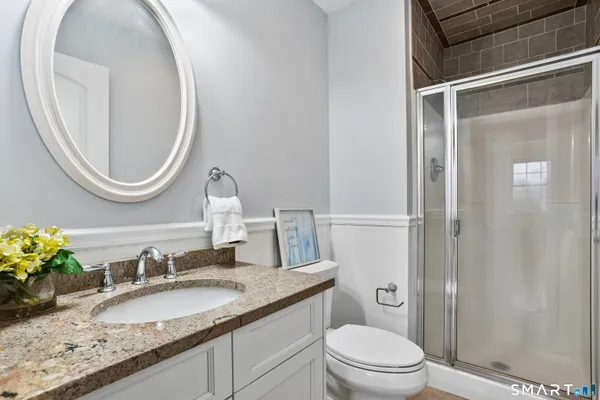 a bathroom with a granite countertop toilet a sink and a mirror