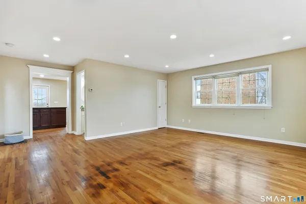 a view of an empty room with wooden floor and a window