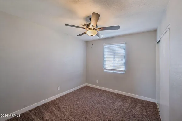 an empty room with windows and fan