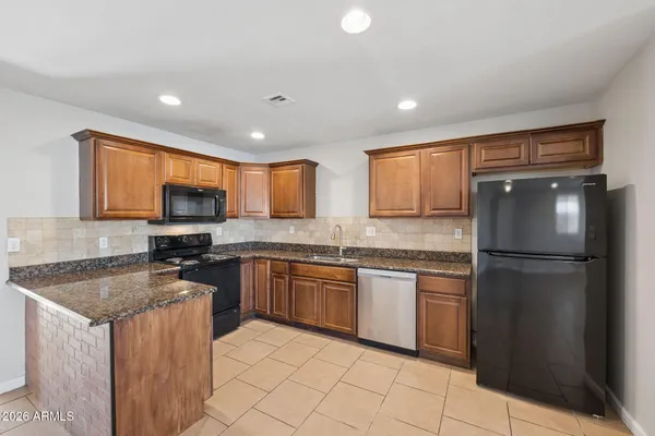a kitchen with granite countertop stainless steel appliances a refrigerator sink and microwave