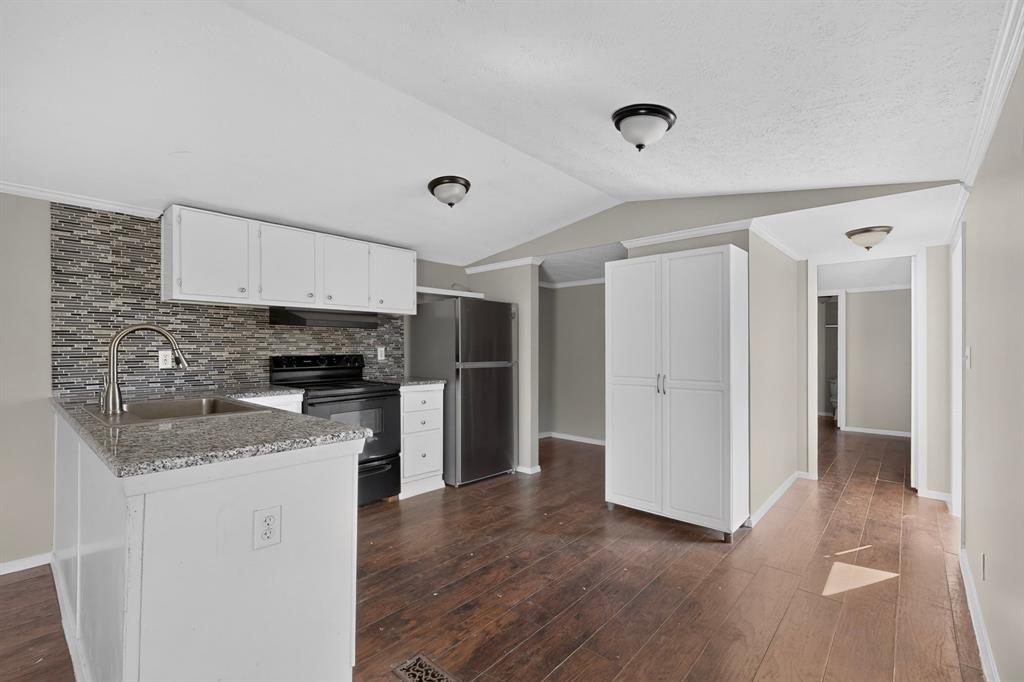 15281 Stice Road Krum, TX 76249 - Photo 5 of 22 Kitchen featuring wood-finish flooring, white cabinetry, granite-style countertops, mosaic tile backsplash, and stainless steel appliances