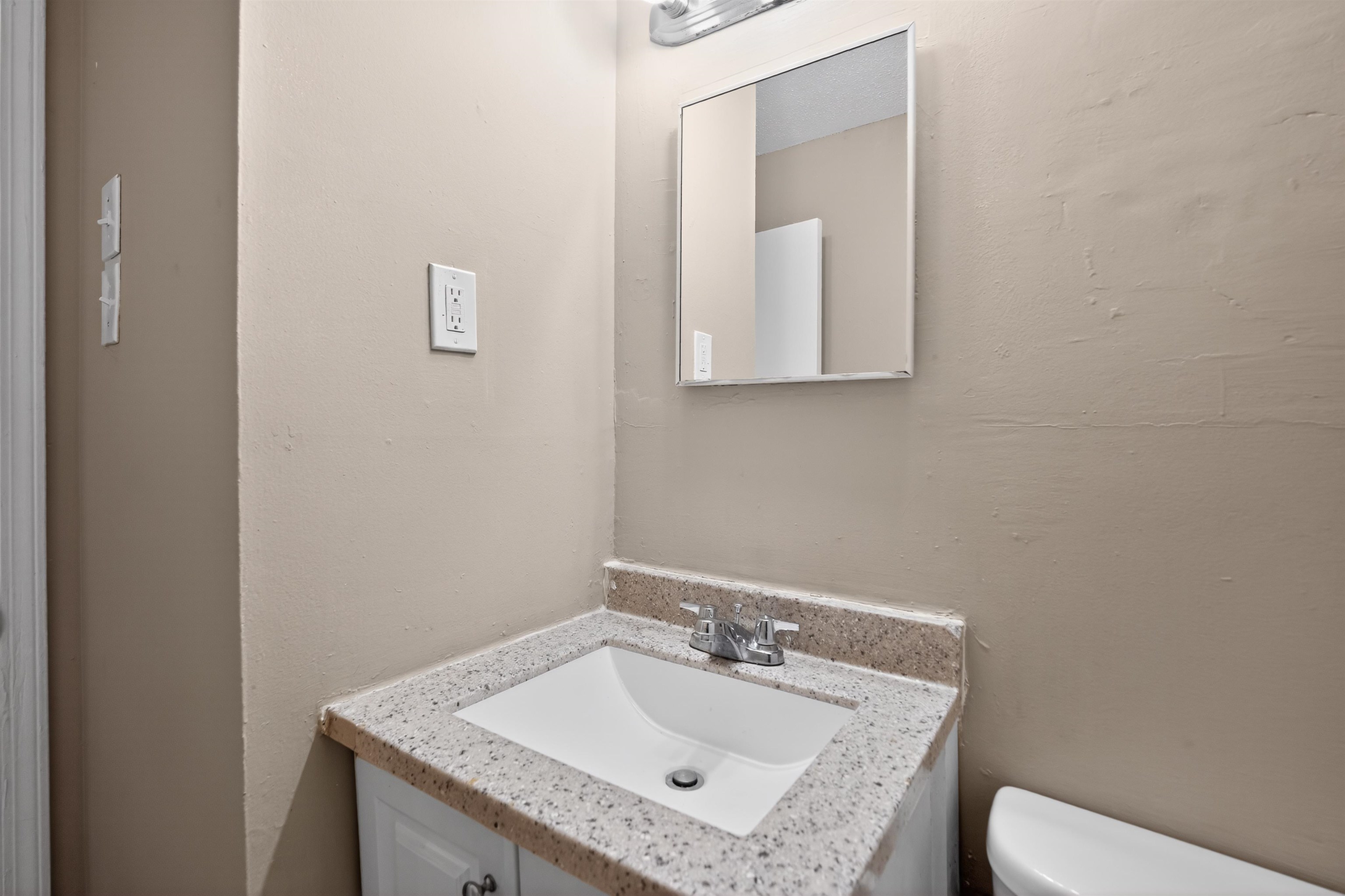 3608 Cane Ridge Drive Memphis, TN 38109 - Photo 27 of 31 Vanity featuring a speckled countertop, integrated sink, and chrome faucet