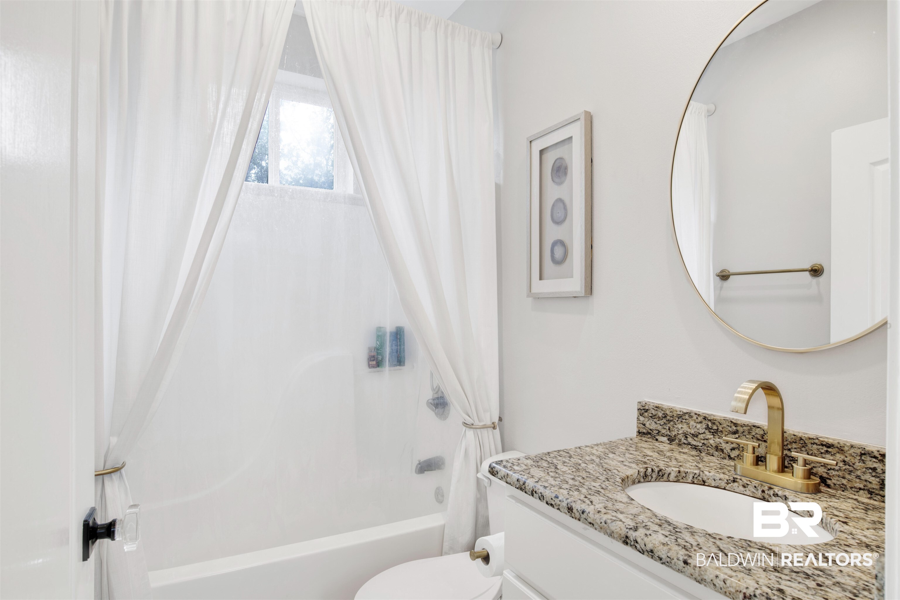 30351 River Road Orange Beach, AL 36561 - Photo 23 of 44 Bathroom featuring a white bathtub, window with privacy curtains, and a vanity with a granite-style countertop