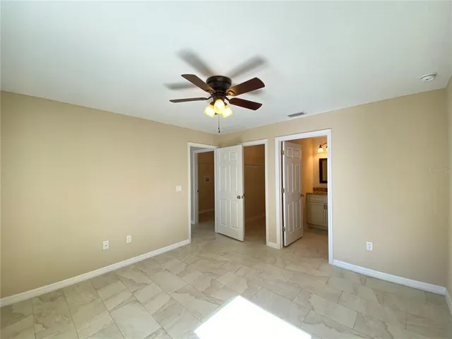an empty room with closet and a ceiling fan