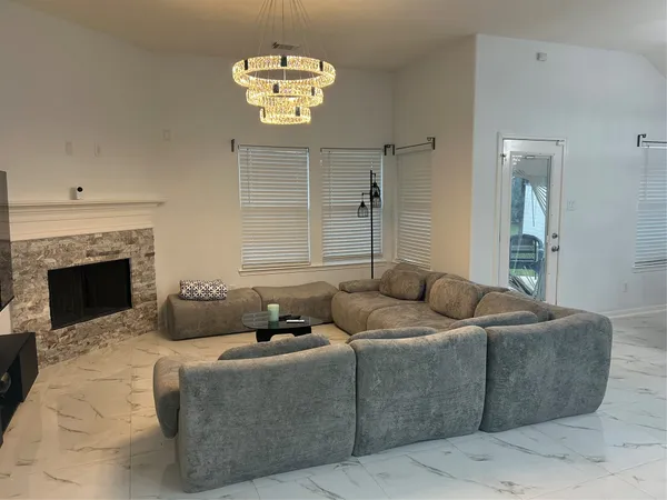 a living room with furniture a fireplace and a chandelier