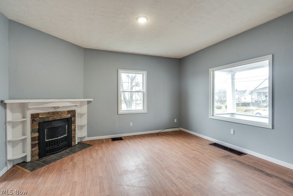 1607 9th Street Southwest Canton, OH 44706 - Photo 6 of 41 Living area featuring a stone-faced fireplace with white mantel and built-in shelving, wood-finish flooring, light gray wall paint, a window, and a recessed ceiling light