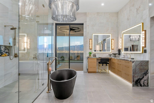 2867 East Granite Way St. George, UT 84790 - Photo 28 of 69 Contemporary bathroom featuring a freestanding black soaking tub, a spacious glass-enclosed shower with a rainfall showerhead, and dual vanities with illuminated mirrors