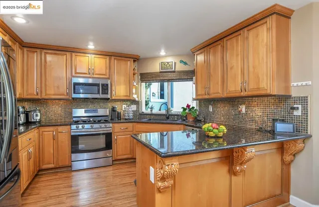 a kitchen with stainless steel appliances granite countertop a sink a stove and cabinets