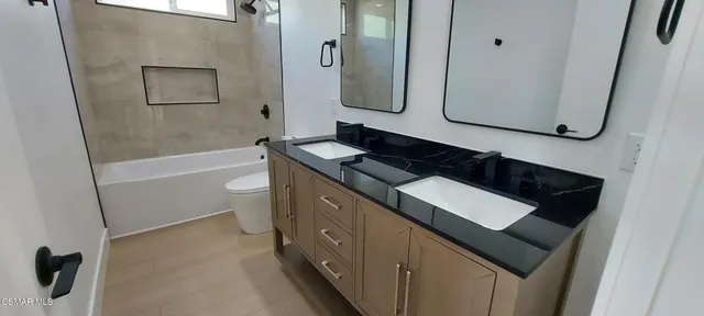 a bathroom with a granite countertop sink a toilet and bathtub