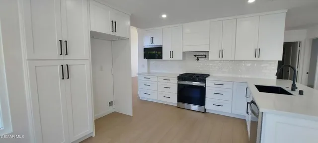 a kitchen with white cabinets and stainless steel appliances