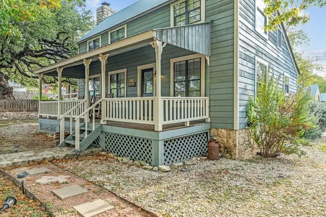 a view of a wooden house with a small yard and wooden fence