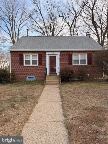 a front view of a house with yard and trees in the background